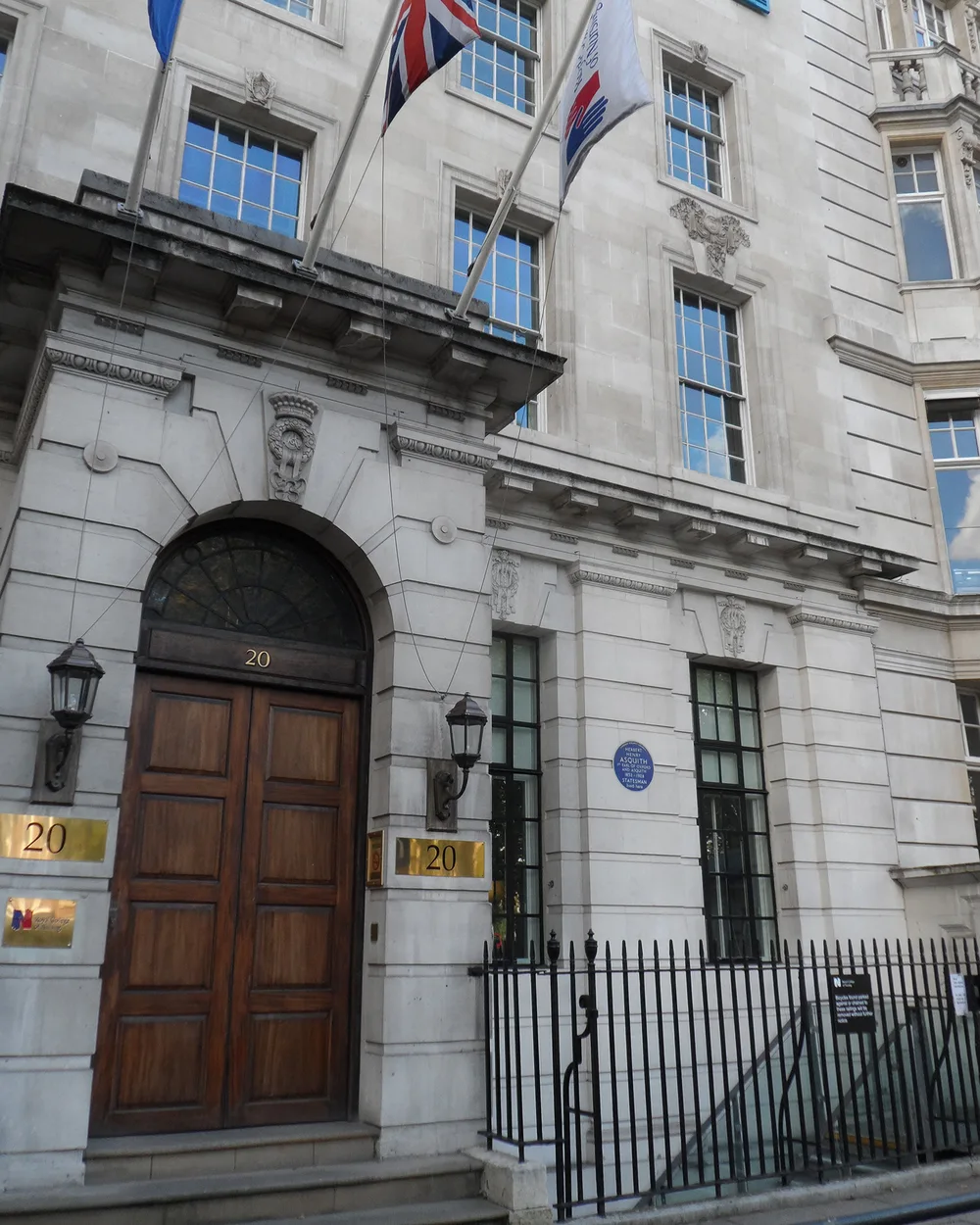 The entrance of 20 Cavendish Square, with its arched wooden doors and flags above